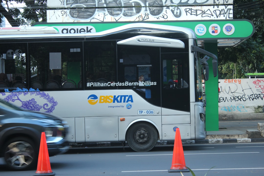 a-white-bus-driving-down-a-street-next-to-traffic-cones-vqxi4-11cdm