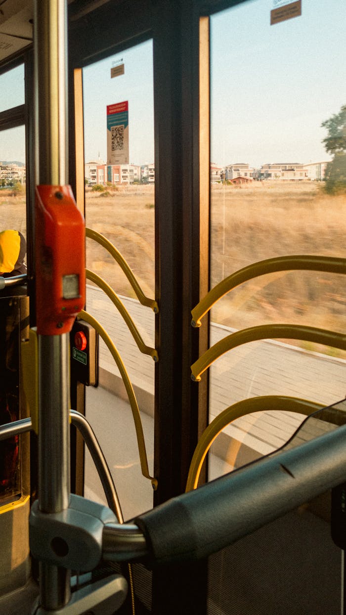 Interior view of a bus showing open doors and a sunny urban landscape outside.